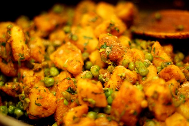 garnishing-dry-aloo-peas-curry-with-sprinkle-of-chaat-masala-and-fresh-cilantro